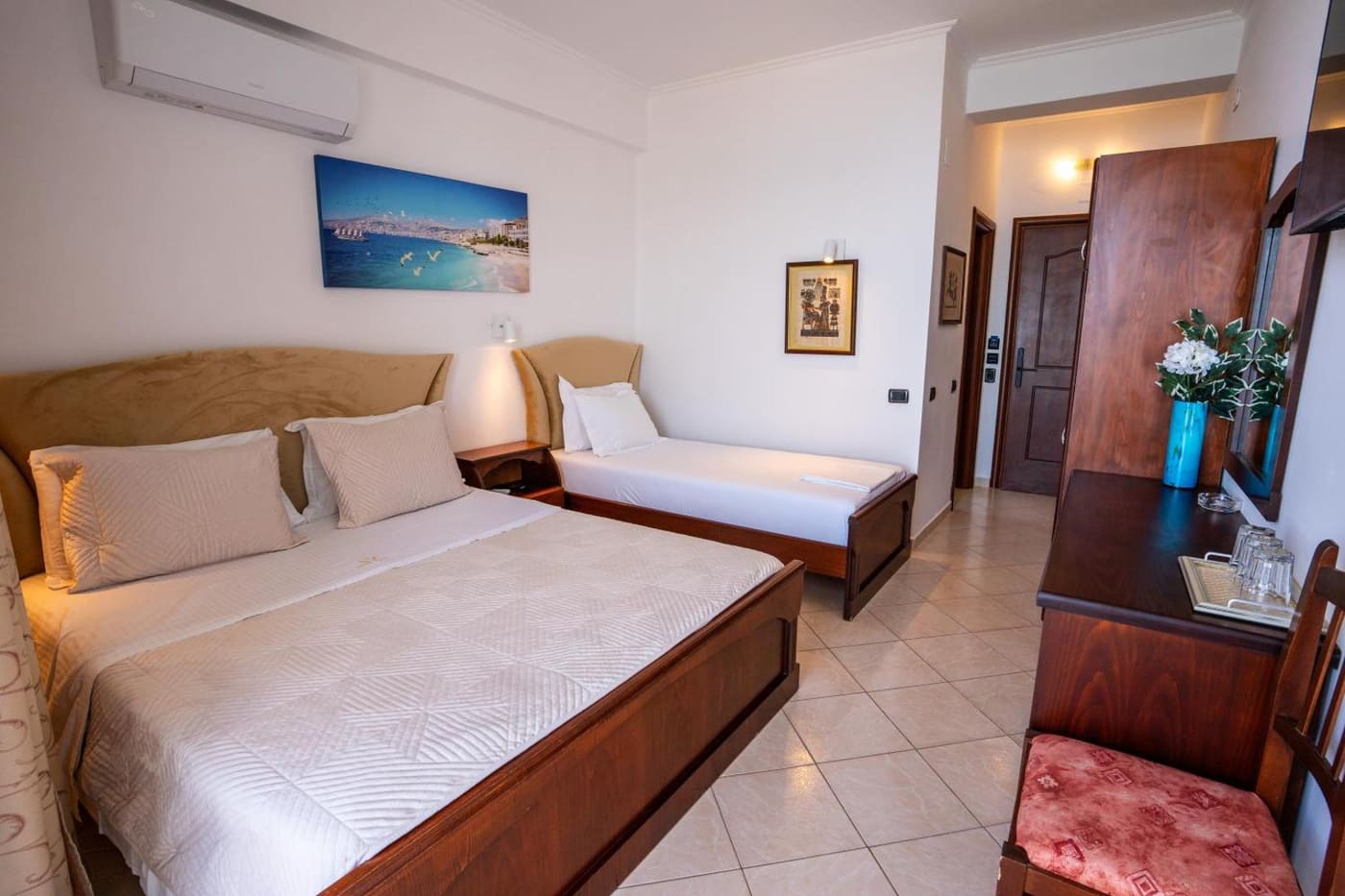 A triple room, with a picture of the bay on the wall